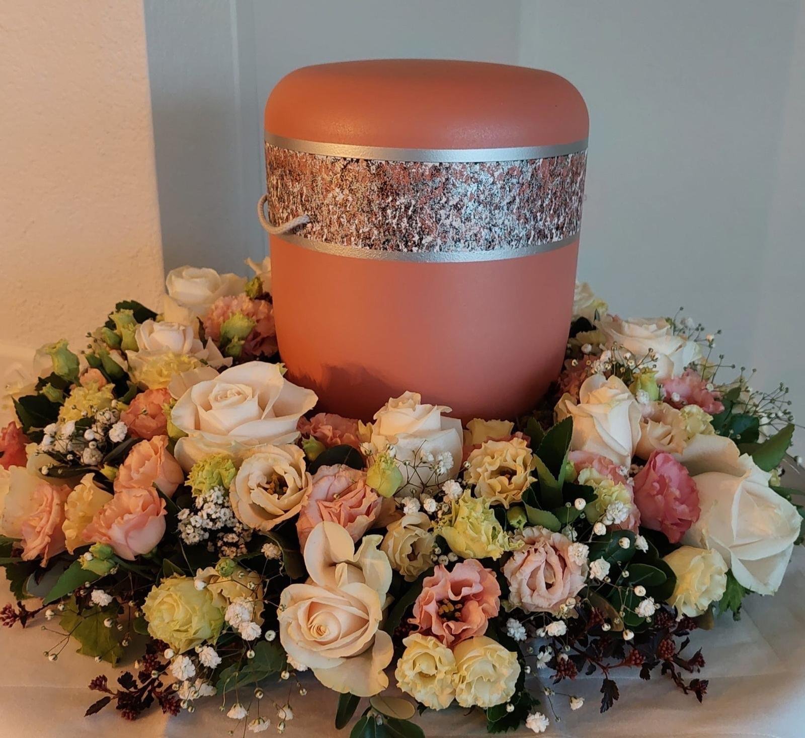 Urne umkränzt von pastellfarbenen Rosen